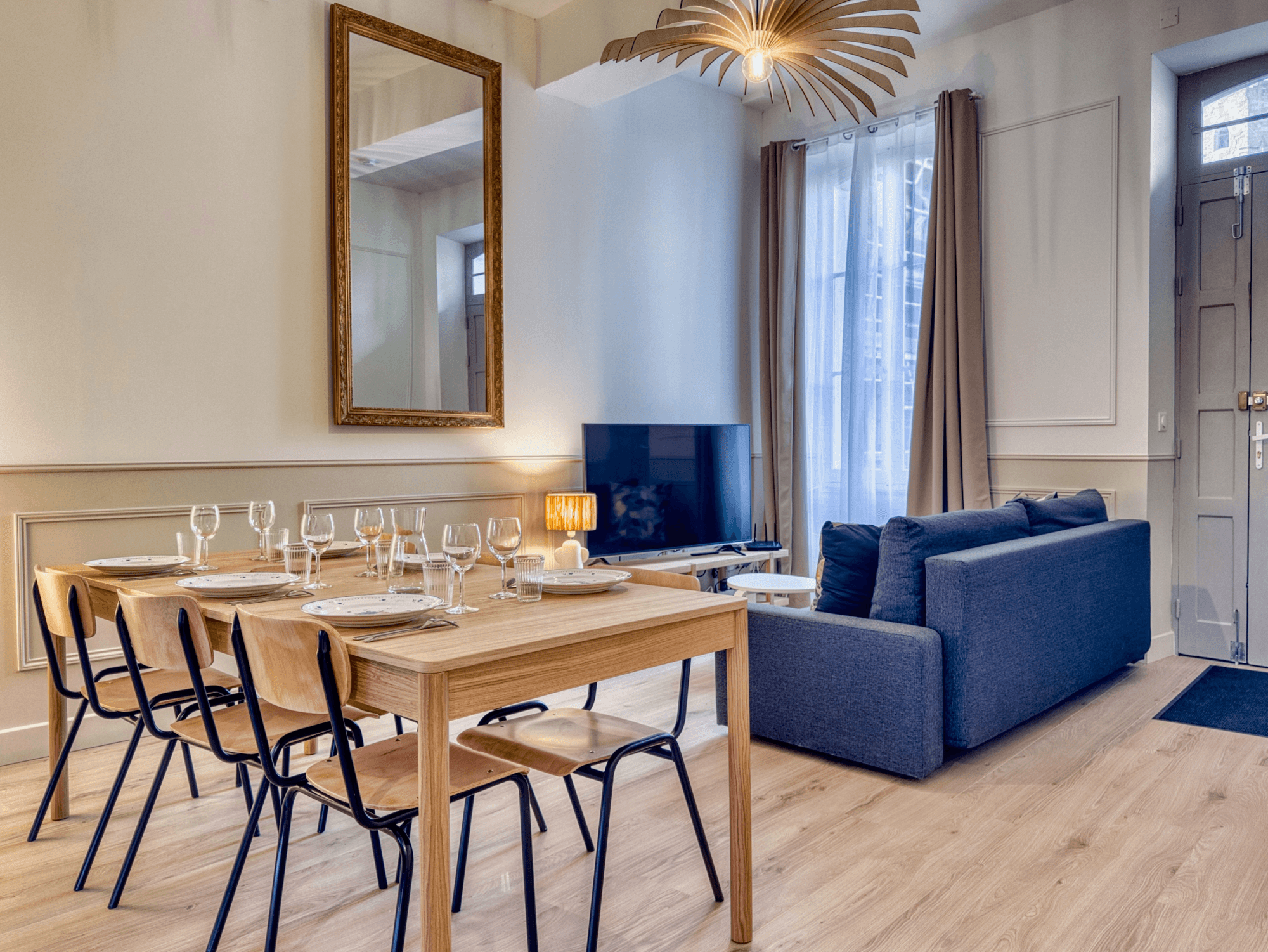 Salon avec canapé bleu, entrée indépendante et table dressée pour six
